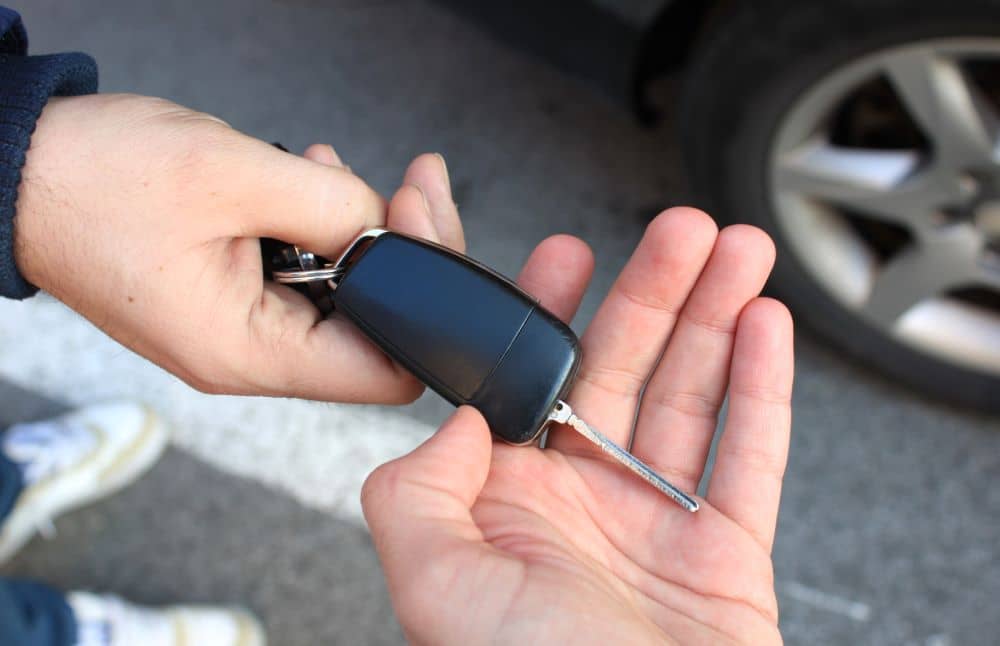 Seller handing over car keys to buyer.